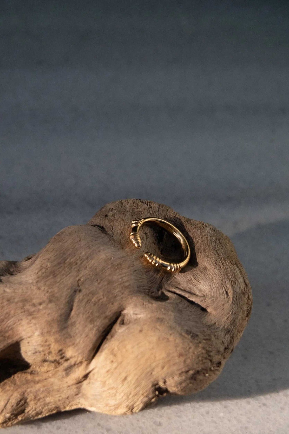 Tribal ring in gold-toned metal, featuring a slim open band with textured coiled details at the ends