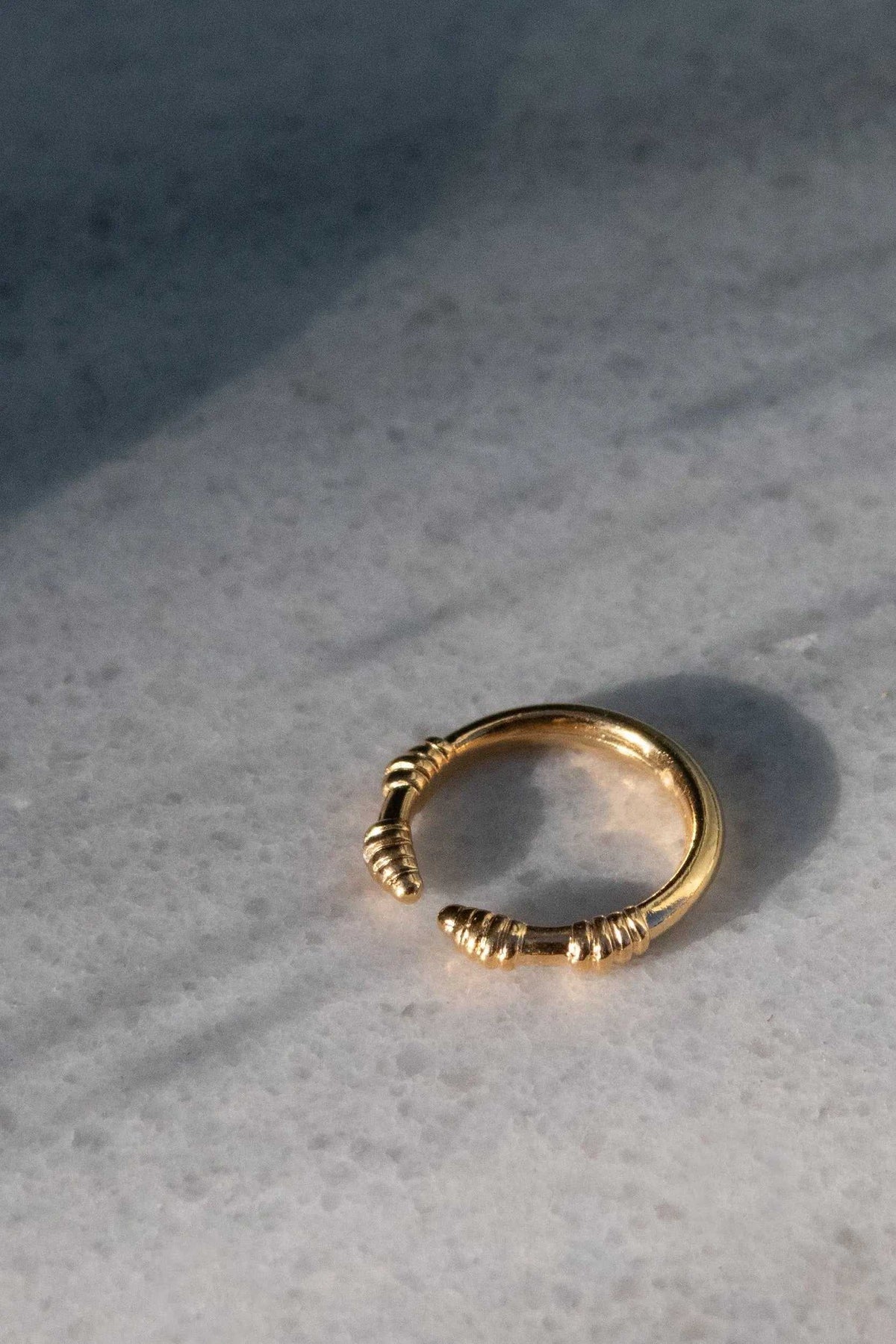 Tribal ring in gold-tone metal with a slim adjustable band and sculpted, ribbed detailing at the ends