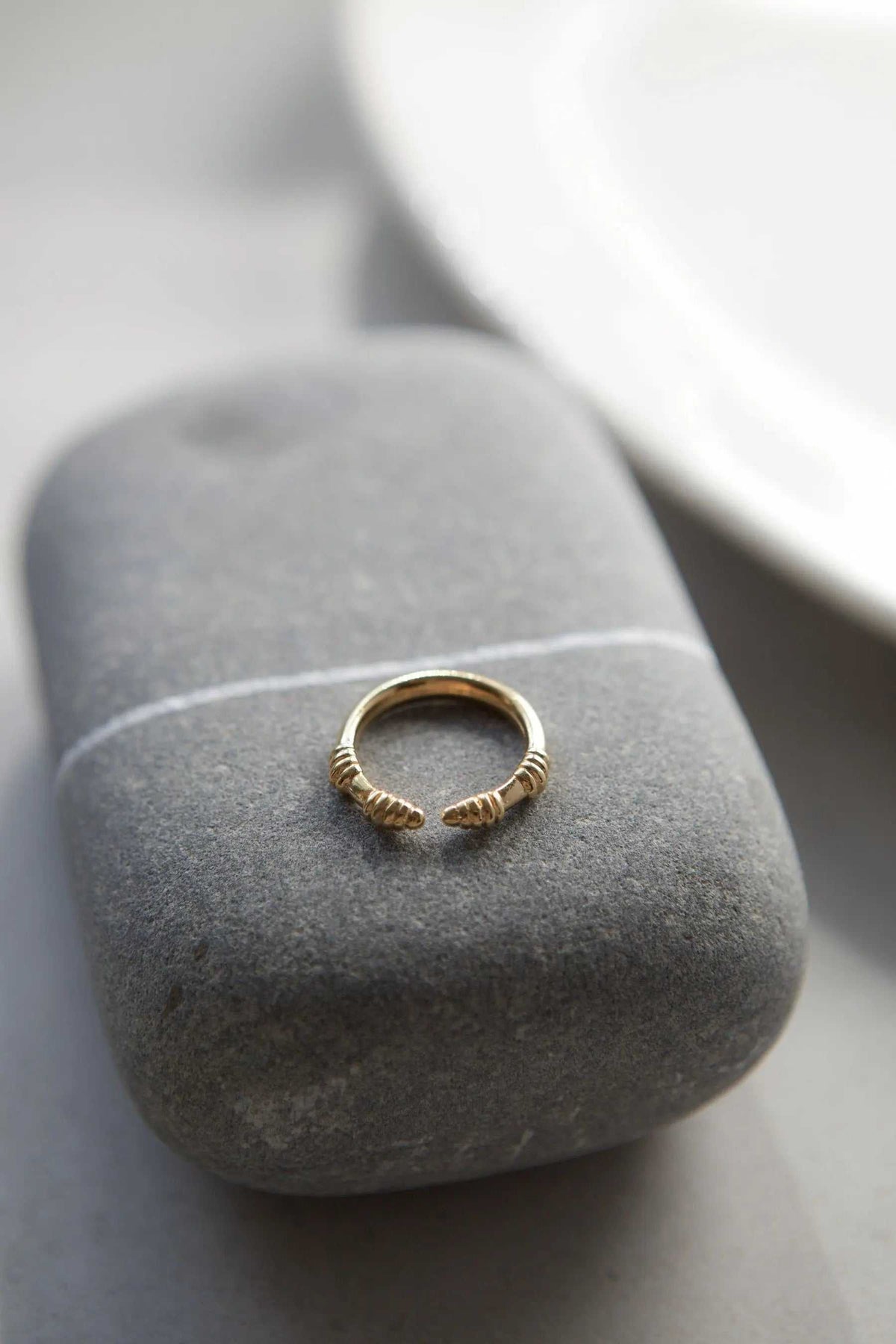 Tribal ring in gold-tone metal with a slim open adjustable band and textured ribbed ends