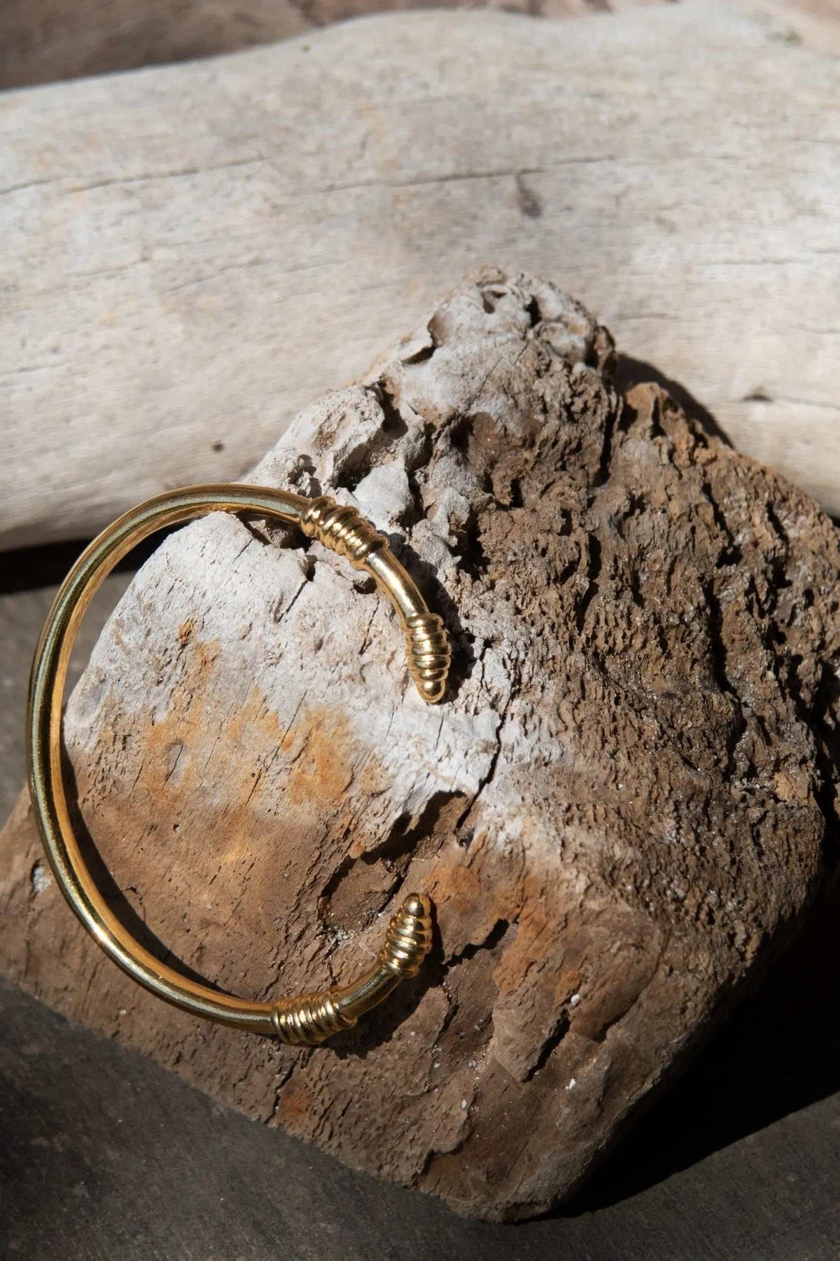 Tribal slim Bracelet in polished gold-tone metal, with a narrow open cuff and wrapped coil details at both ends