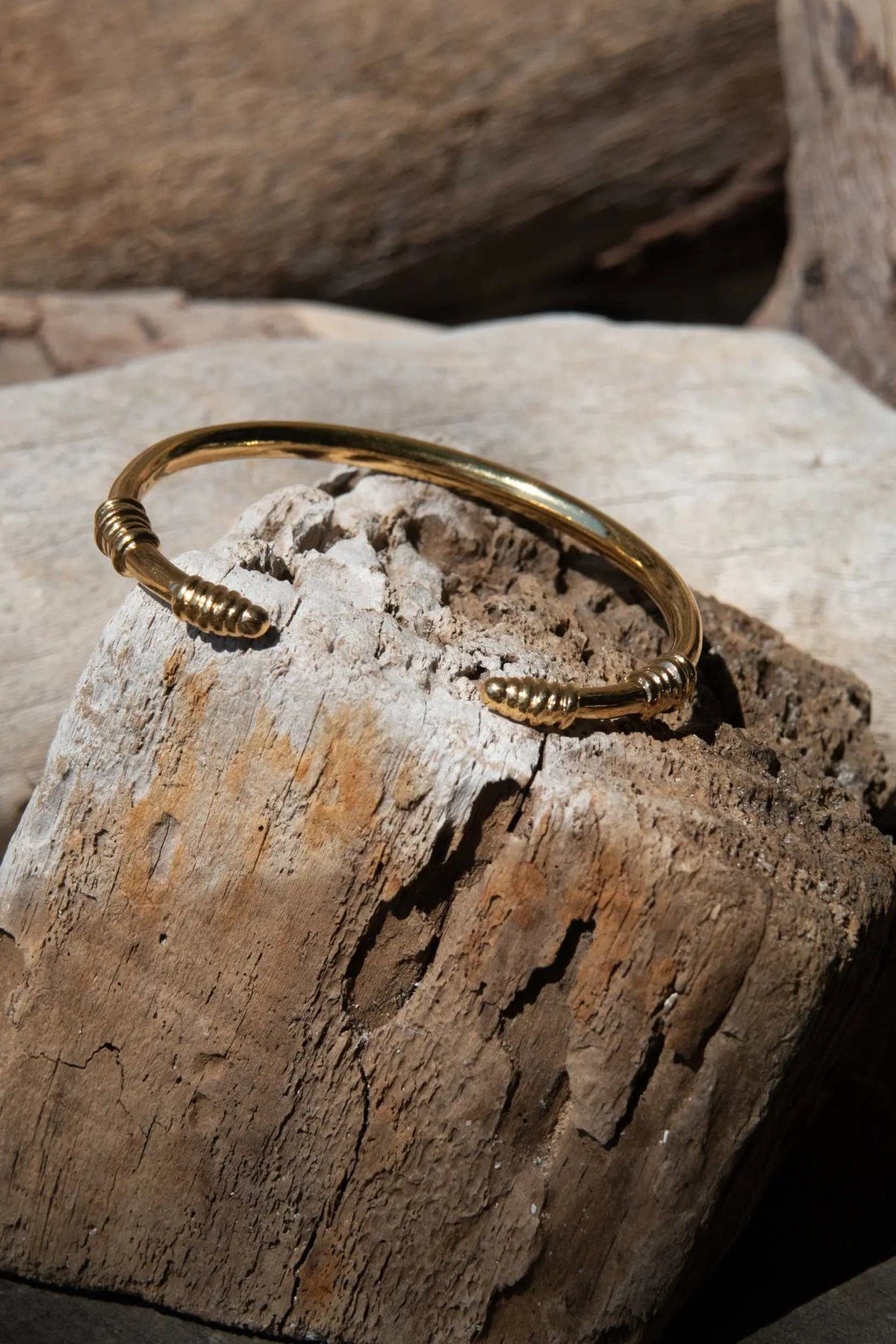 Tribal slim Bracelet in gold-tone metal, with a slim open cuff and coiled tribal-style details at both ends