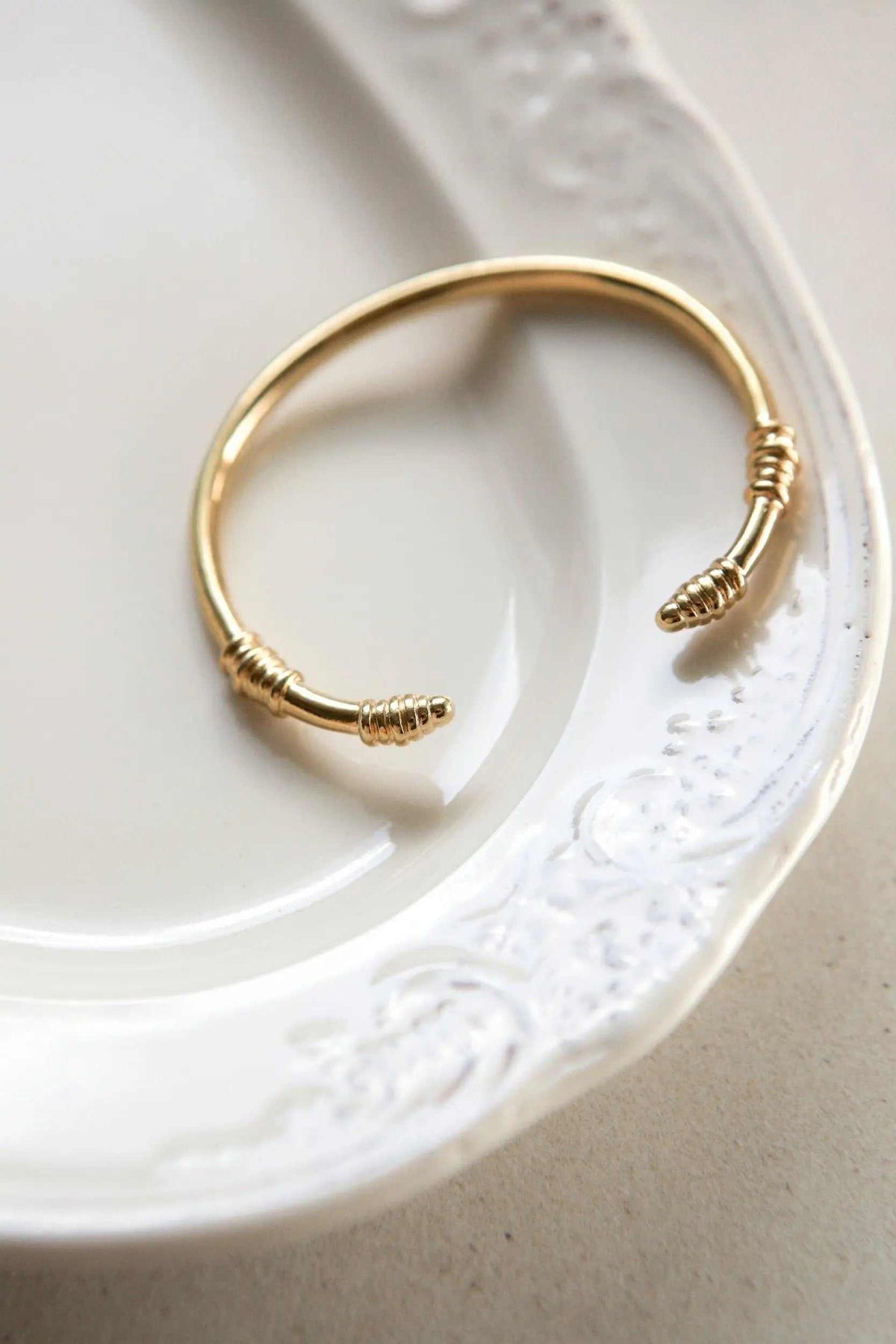 Tribal slim Bracelet with a slim gold-tone open cuff and coiled tribal-style ends in a smooth metal finish