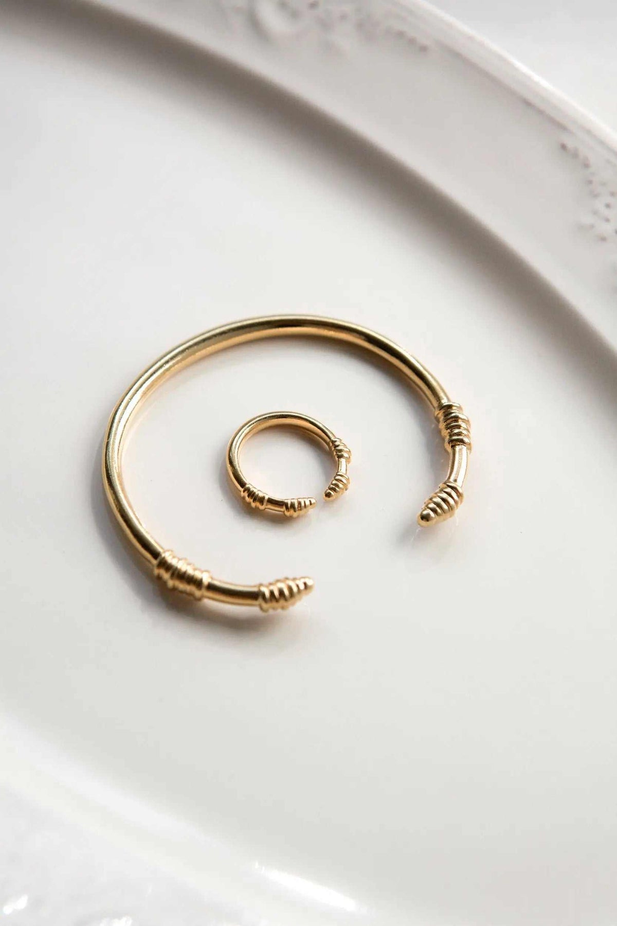 Tribal slim Bracelet in gold-tone metal, featuring an adjustable open cuff and a smaller matching spiral ring