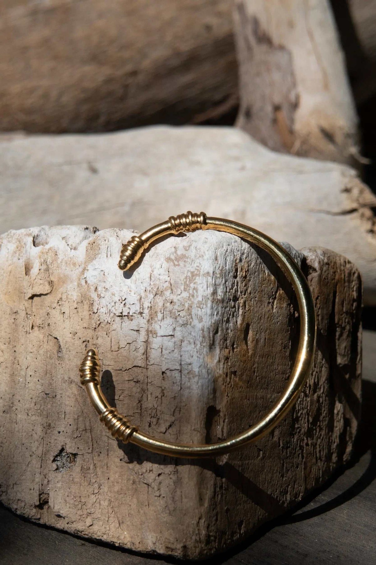 Tribal slim Bracelet in gold-tone metal, with a slim open cuff and wrapped tribal-style detailing at both ends.