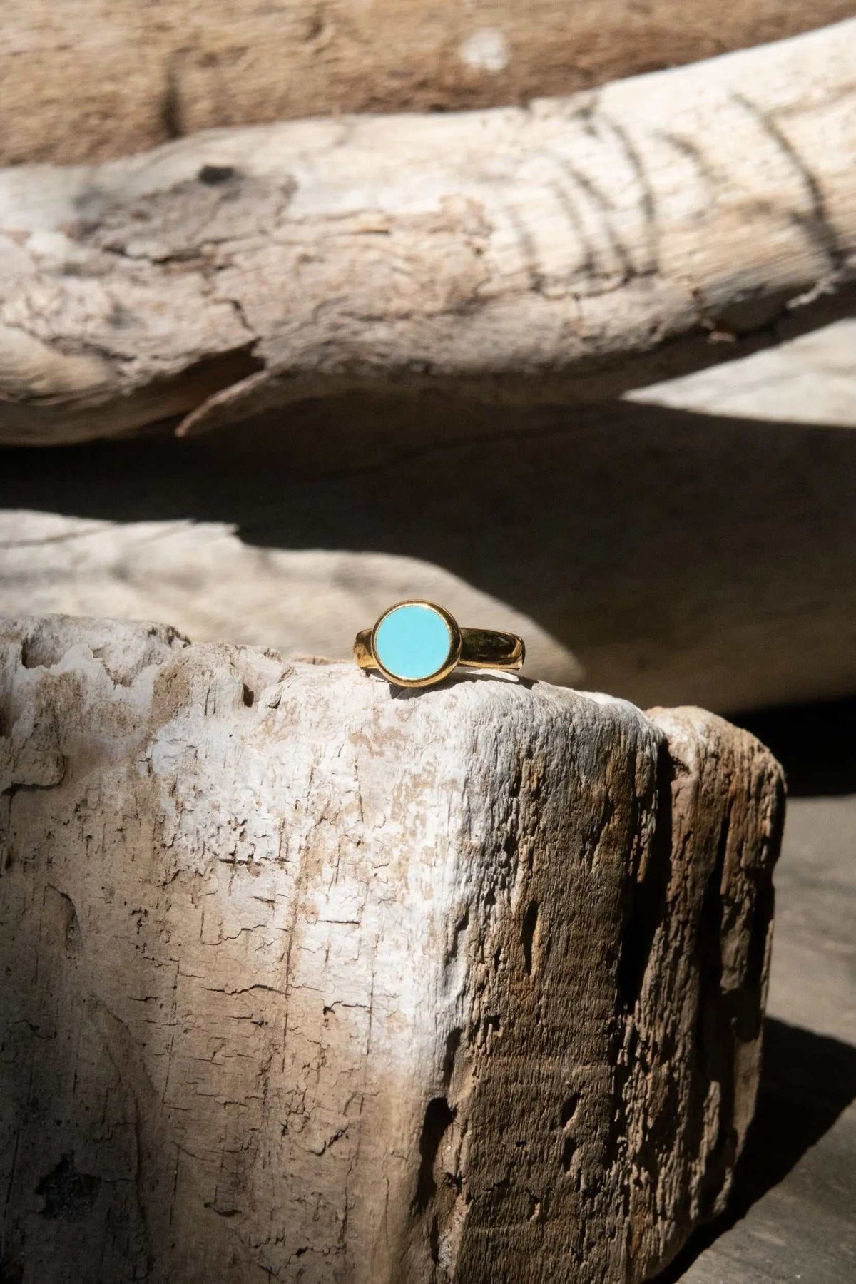 Turquoise Womens ring with a round turquoise-colored stone set in a polished gold-tone band with an open design
