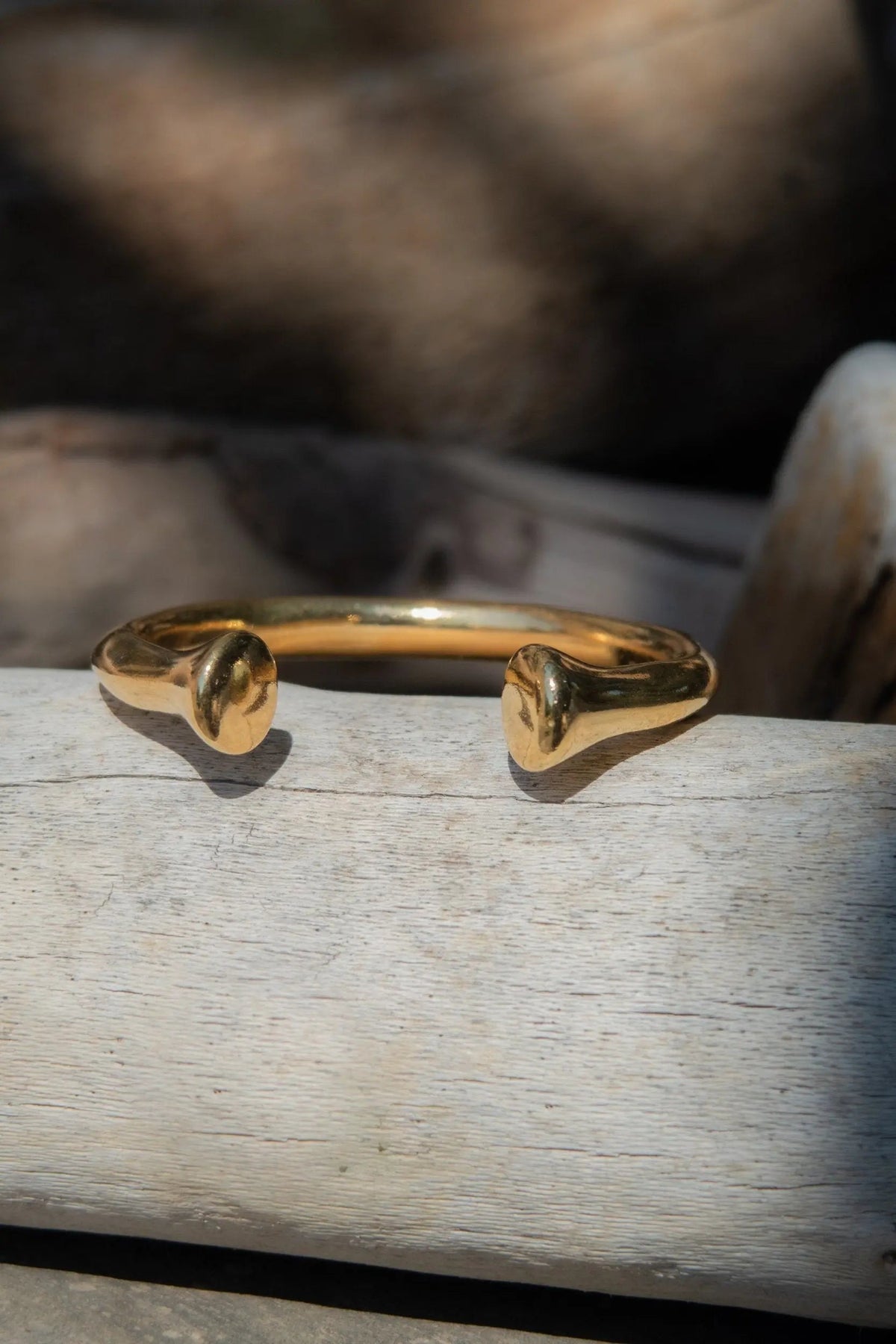 URGO Gold Bracelet is a polished gold-tone open bangle with sculpted curved ends and a thick, rounded band