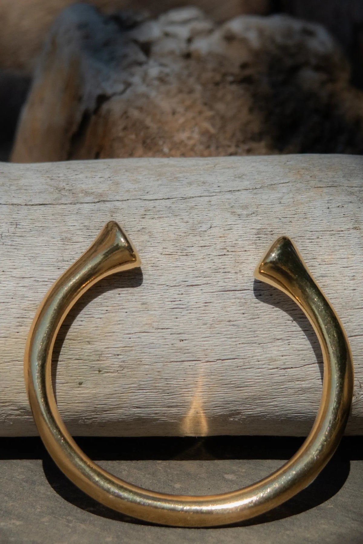 URGO Gold Bracelet, thick gold-tone metal open cuff with curved arms, flared pointed ends, and a smooth rounded band