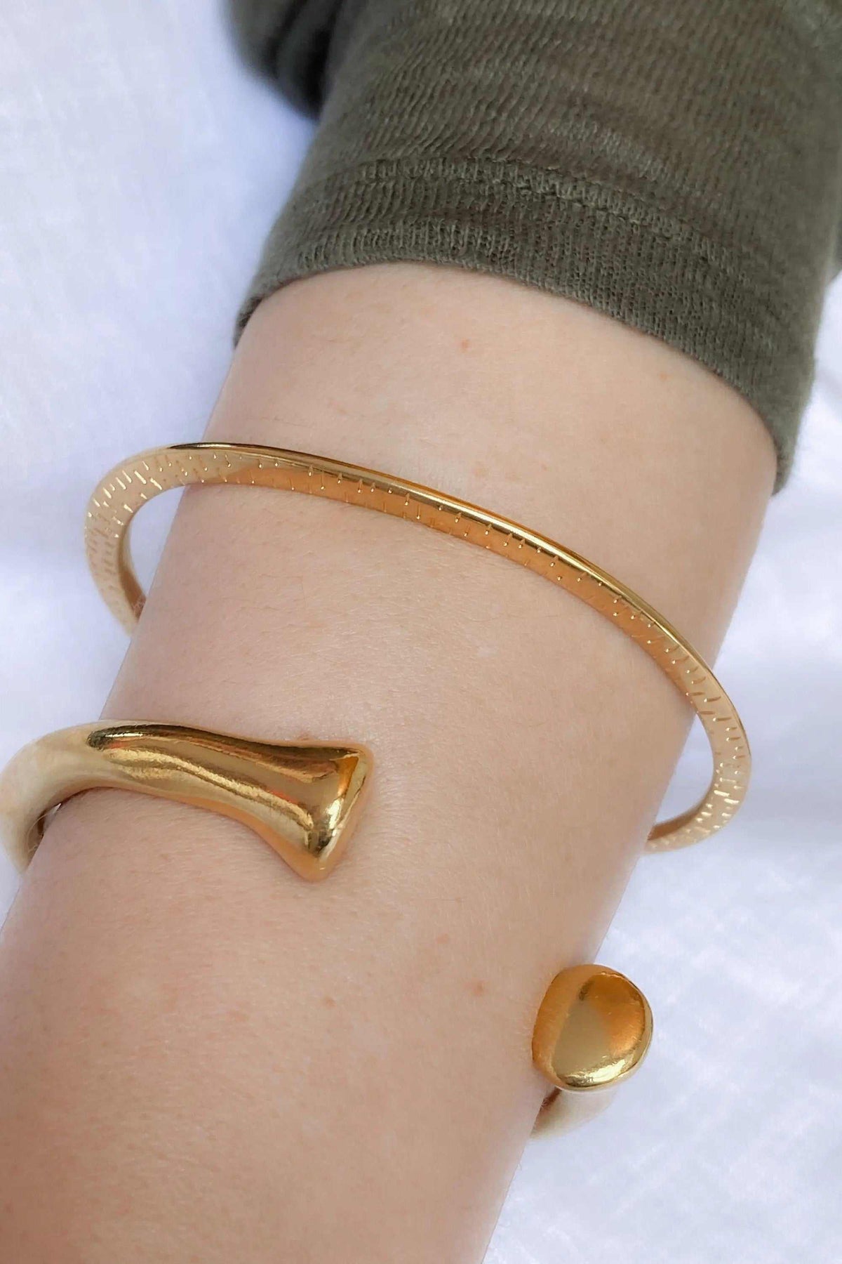 URGO Gold Bracelet, a gold-tone open cuff bangle with a slim textured band and sculptural tapered ends