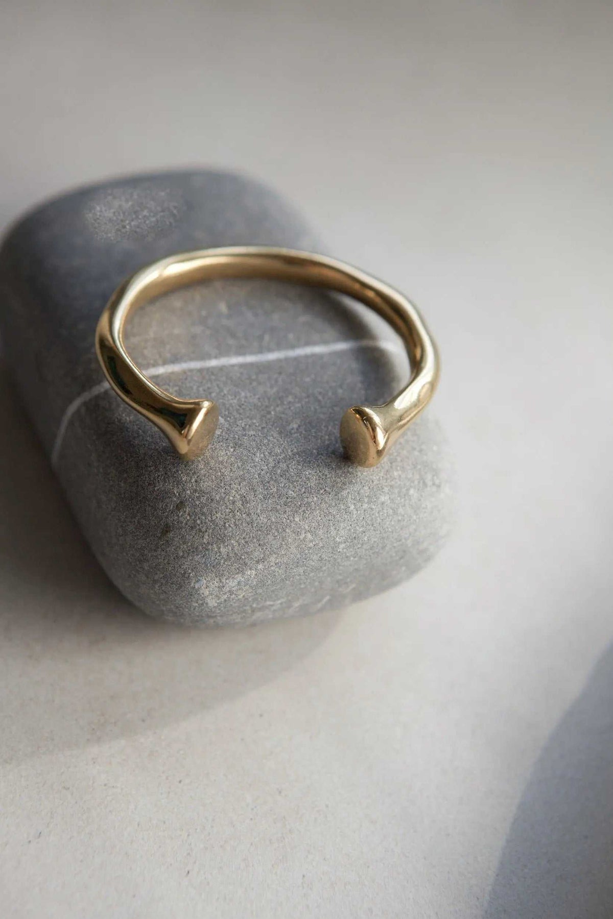 URGO Gold Bracelet, polished gold-tone open bangle with a smooth rounded band and sculpted tapered ends