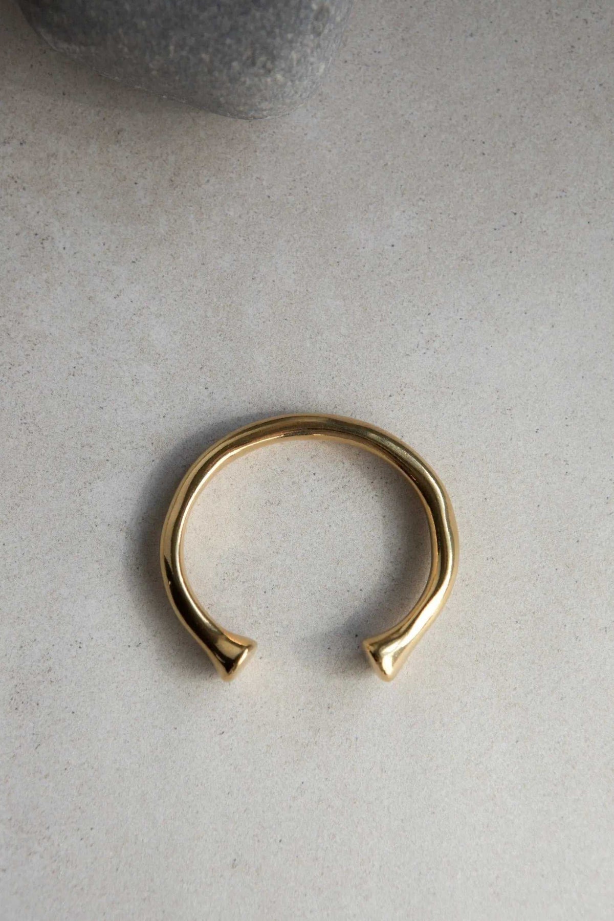 URGO Gold Bracelet, a polished gold-tone open cuff bangle with a smooth rounded band and tapered ends
