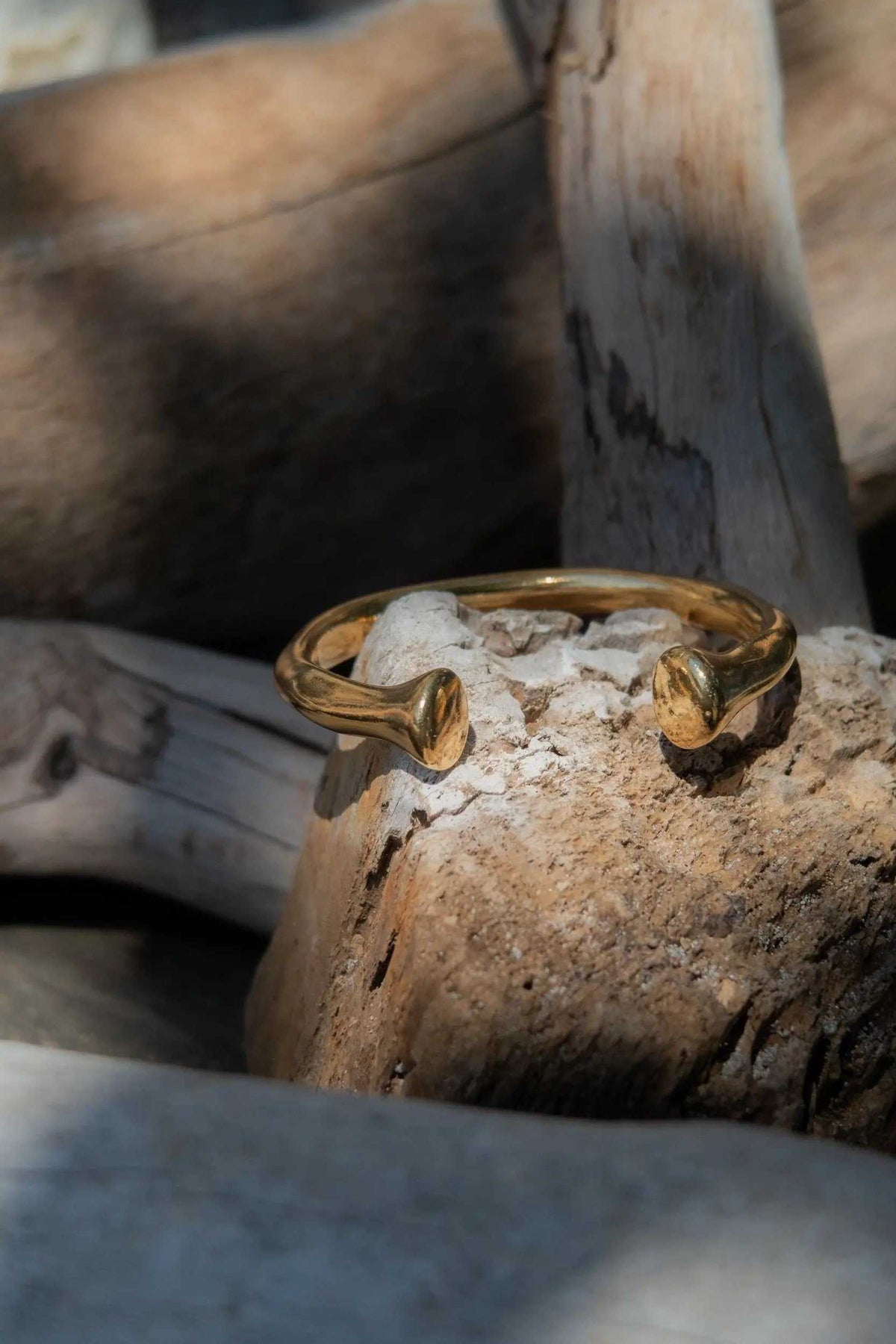 URGO Gold Bracelet, a thick gold-tone open cuff bangle with sculpted curved ends and an organic textured finish