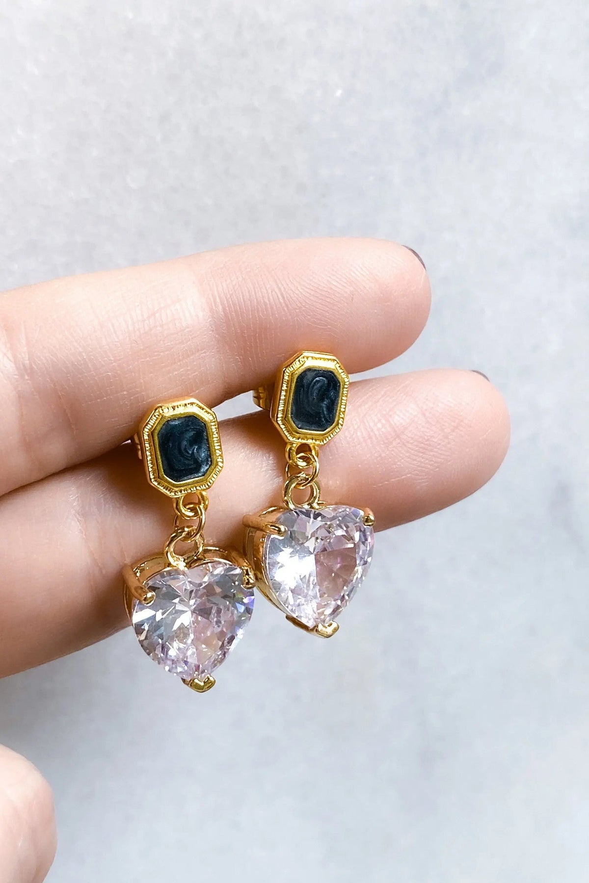 Zircon Heart Earrings with clear heart-cut stones, black rectangular studs and gold-tone settings