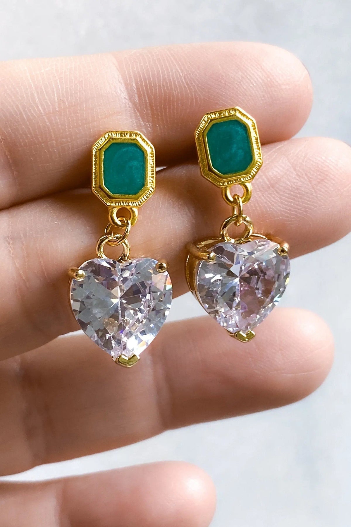 Zircon Heart Earrings with gold-tone settings, deep green rectangular studs, and sparkling clear heart-shaped drops.