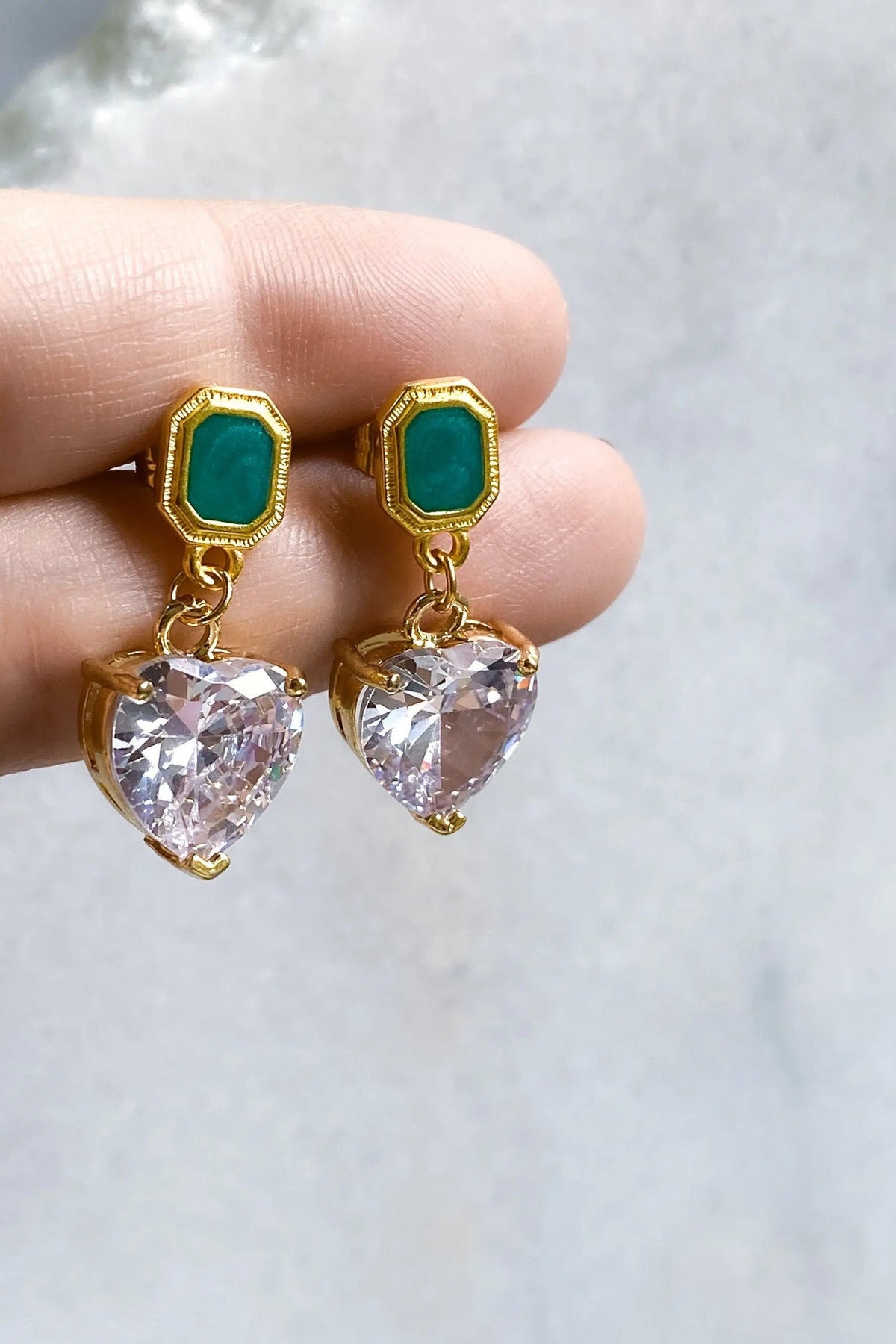 Zircon Heart Earrings with gold-tone settings, emerald-green rectangular studs, and large clear faceted heart-shaped stones